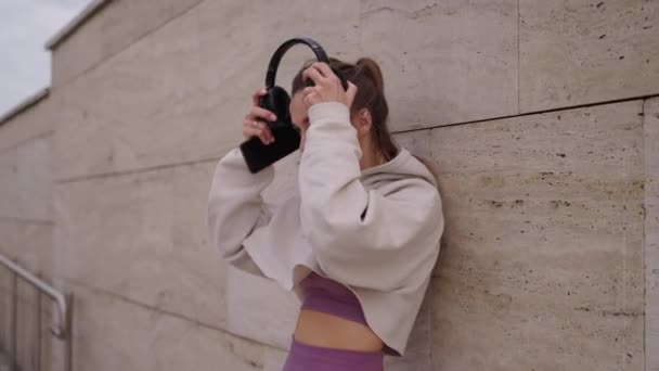 Sportovní žena dává bezdrátová sluchátka pro poslech hudby z chytrého telefonu — Stock video