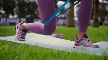 Dışarıda spor yapıyor, direniş bandıyla kalça egzersizi yapıyor.