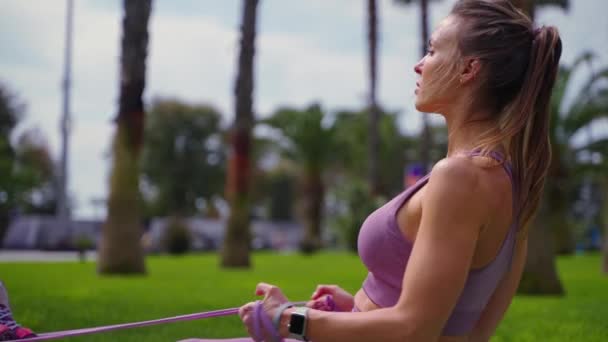 Entrenamiento de fuerza con banda elástica en la zona del parque en la mañana de verano — Vídeos de Stock