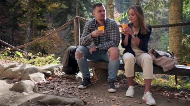 Zwei müde Besucher des Naturparkgeländes, Mann und Frau trinken Tee in der Natur — Stockvideo