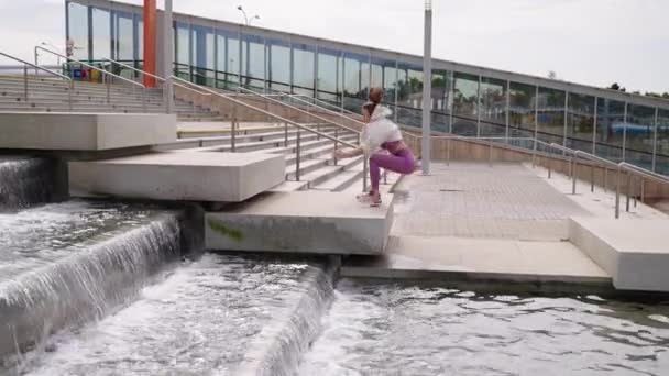 Atletische vrouw springt over trappen in modern stadspark, sportieve training — Stockvideo