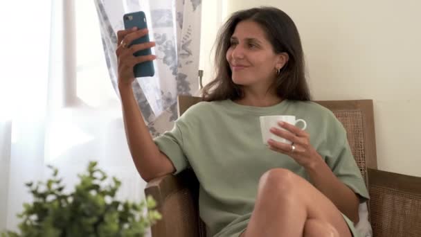 Boldog nő nézi a képeket a szociális hálók, okostelefon, pihentető egyedül otthon — Stock videók