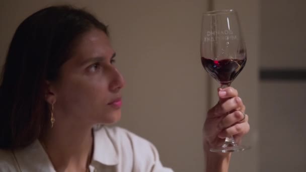 Дегустация вин в ресторане или дома, женщина смотрит красное вино в стакане — стоковое видео