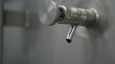 Kırmızı şarap üretimi, çelik fıçı çeşmesinin yakın görüntüsü.