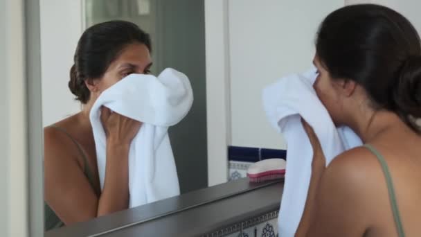 Volwassen brunette vrouw is vegen haar gezicht na wassen in badkamer — Stockvideo