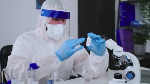 Virologiste regarde flacon avec le vaccin contre le coronavirus en laboratoire médical — Video