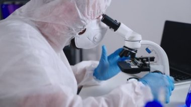 Koronavirüse karşı aşı geliştiriyorum. Mikroskopla çalışan bilim adamı