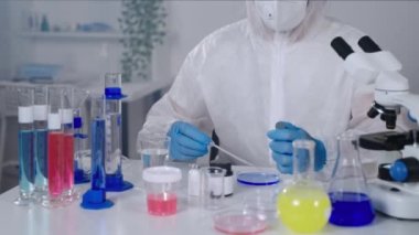 Laboratuvarda tıbbi araştırmalar, erkek bilim adamı petri kabında sıvı karıştırıyor.