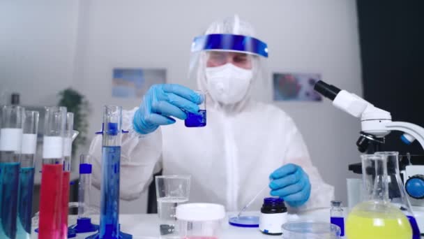 Viroloog onderzoekt nieuw coronavirus in laboratorium en bekijkt vloeistof in flacon — Stockvideo