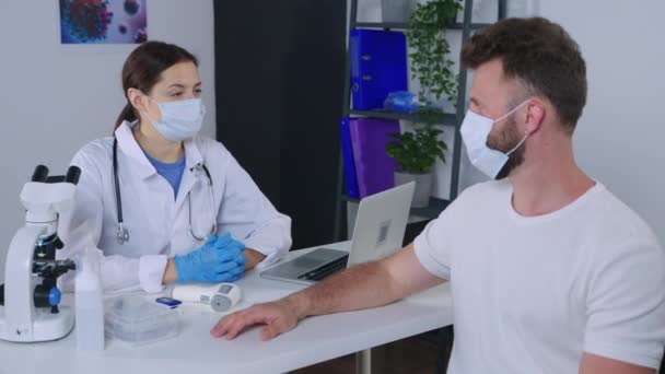 Γιατρός μετρά τη θερμοκρασία του ασθενούς με θερμόμετρο μη επαφής κατά τη διάρκεια του ραντεβού στην κλινική — Αρχείο Βίντεο