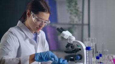 Modern laboratuvarda tıbbi testler, sağlık uzmanı mikroskop altında örnekler inceliyor