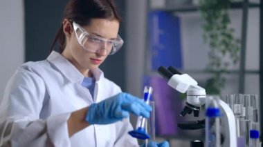 Kimyager kadın test tüpünde reaktörleri karıştırıyor, kimya laboratuarında çalışıyor.