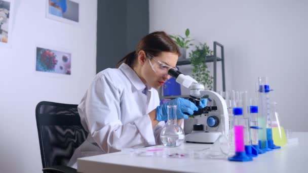 Virolog utforskar prov i mikroskop i modernt laboratorium — Stockvideo