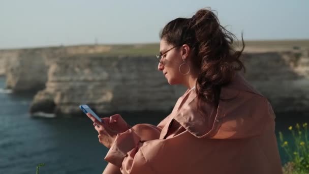 Bruna riflessiva con cellulare vicino al mare — Video Stock