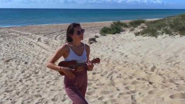Mädchen mit Ukulele am Strand — Stockvideo