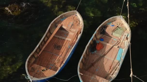 Oude vissersboten zwaaien door zeegolven, afgemeerd nabij de kust — Stockvideo