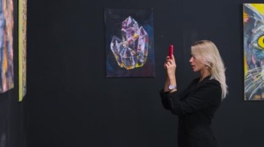 Kadın, modern sanatçının resimleriyle müzede resim çekiyor.