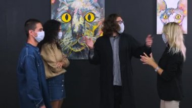 Yüz maskeli insanlar güzel sanat galerilerinde rehberli sergi görüyorlar.