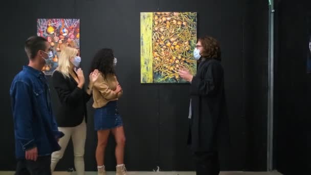Interested in art young people listening to the art guide at the exhibition — Stock Video