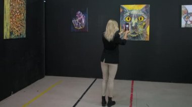 Güzel sanatlar müzesinin bayan ziyaretçisi akıllı telefonla fotoğraf çekiyor.