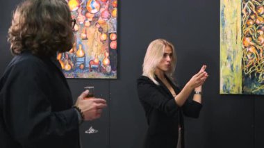 Resim galerisinde ziyaretçileri olan neşeli sanat rehberi