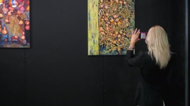 Genç bir kadın güzel sanatlar müzesinde resim çekiyor.