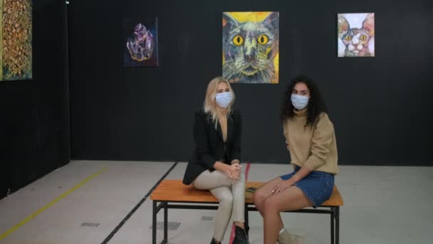 Dua wanita muda sedang mendiskusikan gambar seniman di museum pada pandemi hidup — Stok Video