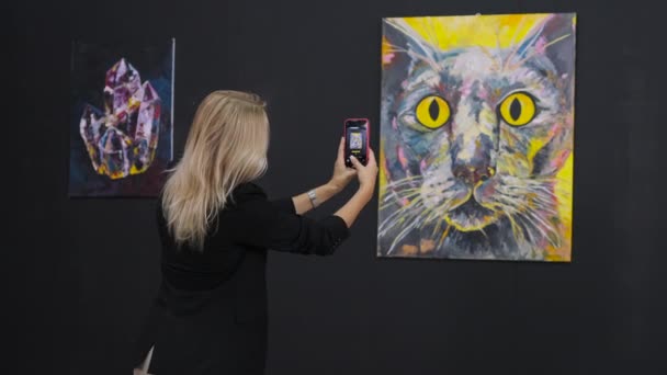 Woman is taking photo by smartphone of modern abstract picture in fine art museum — Stock Video