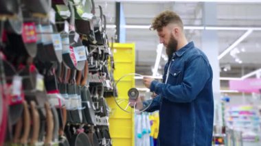 Adam mutfak gereçleri dükkanında ot için kapak seçiyor.