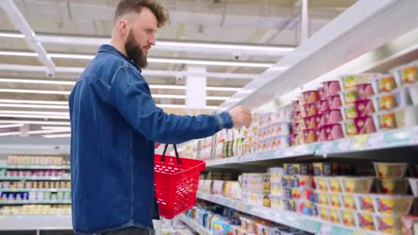 Mannelijke shopper kiest yoghurt voor ontbijt en lunch, winkelen in de supermarkt — Stockvideo