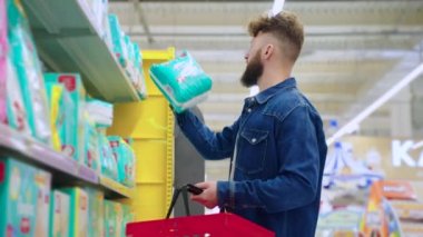 Genç baba süpermarketten yeni doğan bebek için bebek bezi alıyor.