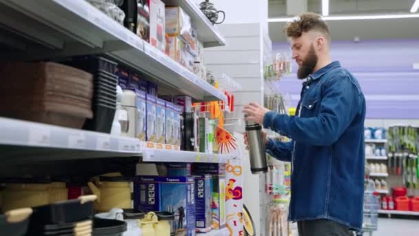 Россия, Сочи - 20 июня 2021 года: покупки в современном супермаркете, взрослый мужчина выбирает термос — стоковое видео