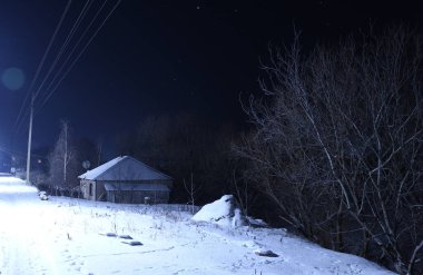 Kış gecesi manzarası, karla kaplı orman, yol ve köy evleri, gece manzarası..