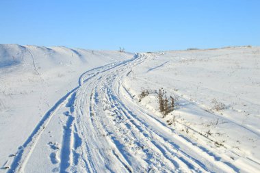 Mavi gökyüzünün arka planında karla kaplı yol.