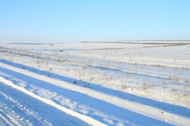 Karlı tarlaları olan bir manzara. Kırsal kesimdeki köyde kış manzarası