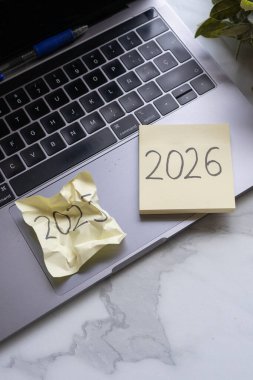 2026 'yı gösteren yapışkan not buruşmuş bir laptopun yanında.