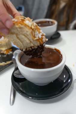 Kahvaltıda sıcak çikolataya batırılmış tatlı brioche ekmeğinin tadını çıkaran kişi.