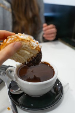 Tatlı brioche tatlısını şekerli ve badem gevreğiyle zengin sıcak çikolatalara batırıyorum.