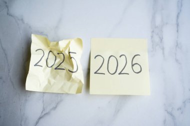 2025 yılının 2026 yılının yanında buruşuk yapışkan bir not.