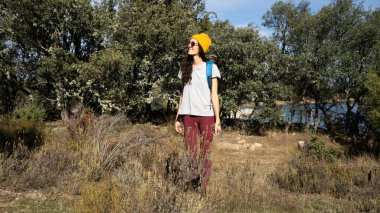 Sarı bereli ve sırt çantalı bir kadın gökyüzüne bakıyor.