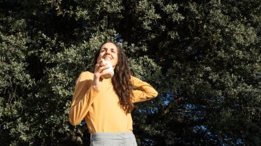 Doğada gülümseyen, bir kupadan içen, mutluluğu ve sağlığı kucaklayan bir kadın.