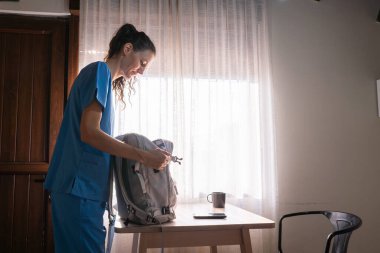 Önlüklü kadın eşyalarını bir sırt çantasına koyup vardiyası için hazırlanıyor.