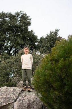 Bir kayanın üzerinde duran çocuk doğa koruma alanında yürüyüş yaparken manzaranın tadını çıkarıyor.