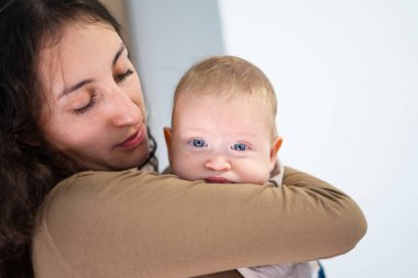 Anne sevgiyle bebeğini kucağına alıp, hassas bir an yaratıyor.