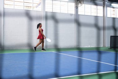 Pickleball oyuncusu bir maçtan sonra elinde raketiyle iç sahada yürüyor.