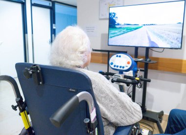 Klinikte interaktif bir video sistemi ile rehabilitasyon terapisi uygulayan yaşlı bir kadın.