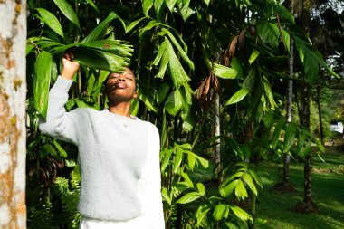Tropikal bir ormanda poz vermek, yaprakların arasından süzülen güneş ışığının tadını çıkarmak.