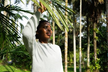 Botanik bahçesinde doğanın tadını çıkaran, palmiye yapraklarına dokunan bir model.