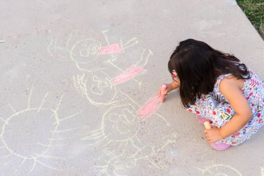 Genç çocuk beton kaldırım tebeşiri kullanarak canlı çizimler yapıyor.