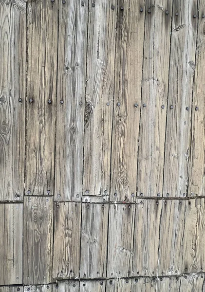 Görünür dokusu, çatlakları ve metal tırnakları olan ahşap bir yüzeye yakın çekim.